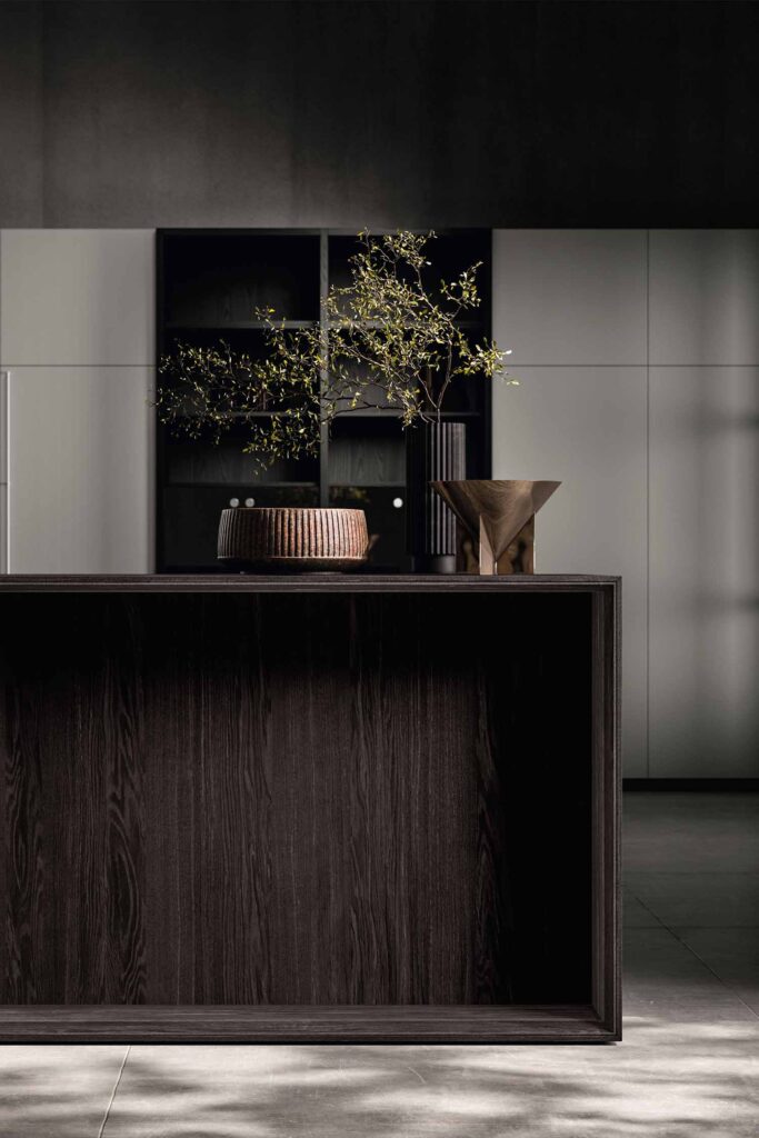 A shot of two kitchen drawers opened to show a highly organized storage system. The top drawer contains cutlery in a dark wooden organizer, while the bottom drawer has a system of movable wooden dividers, with stacks of white plates and bowls.