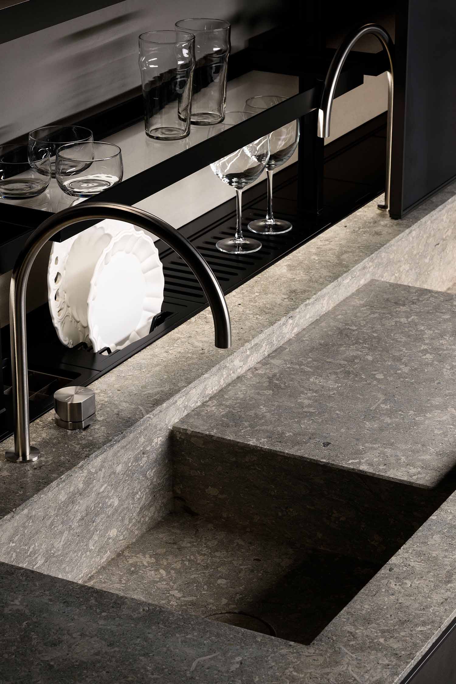 A close-up of a kitchen's built-in, handleless wall cabinets. The cabinets are a light wood veneer with a distinct vertical grain pattern, and an integrated light strip at the bottom illuminates the countertop.