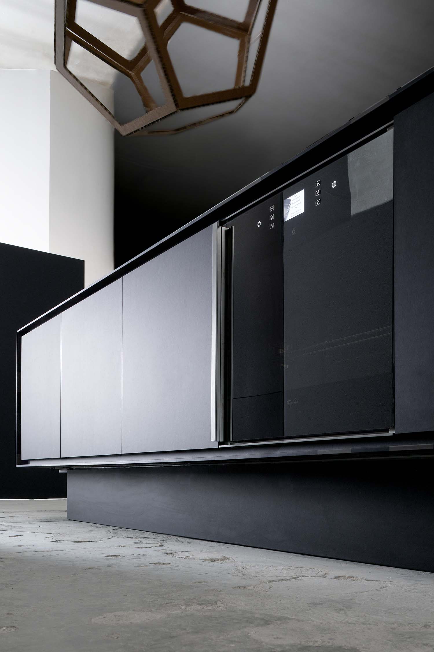 close-up of a modern kitchen sink. The black sink is flush-mounted into a dark countertop, and a sleek, black, gooseneck faucet is visible.