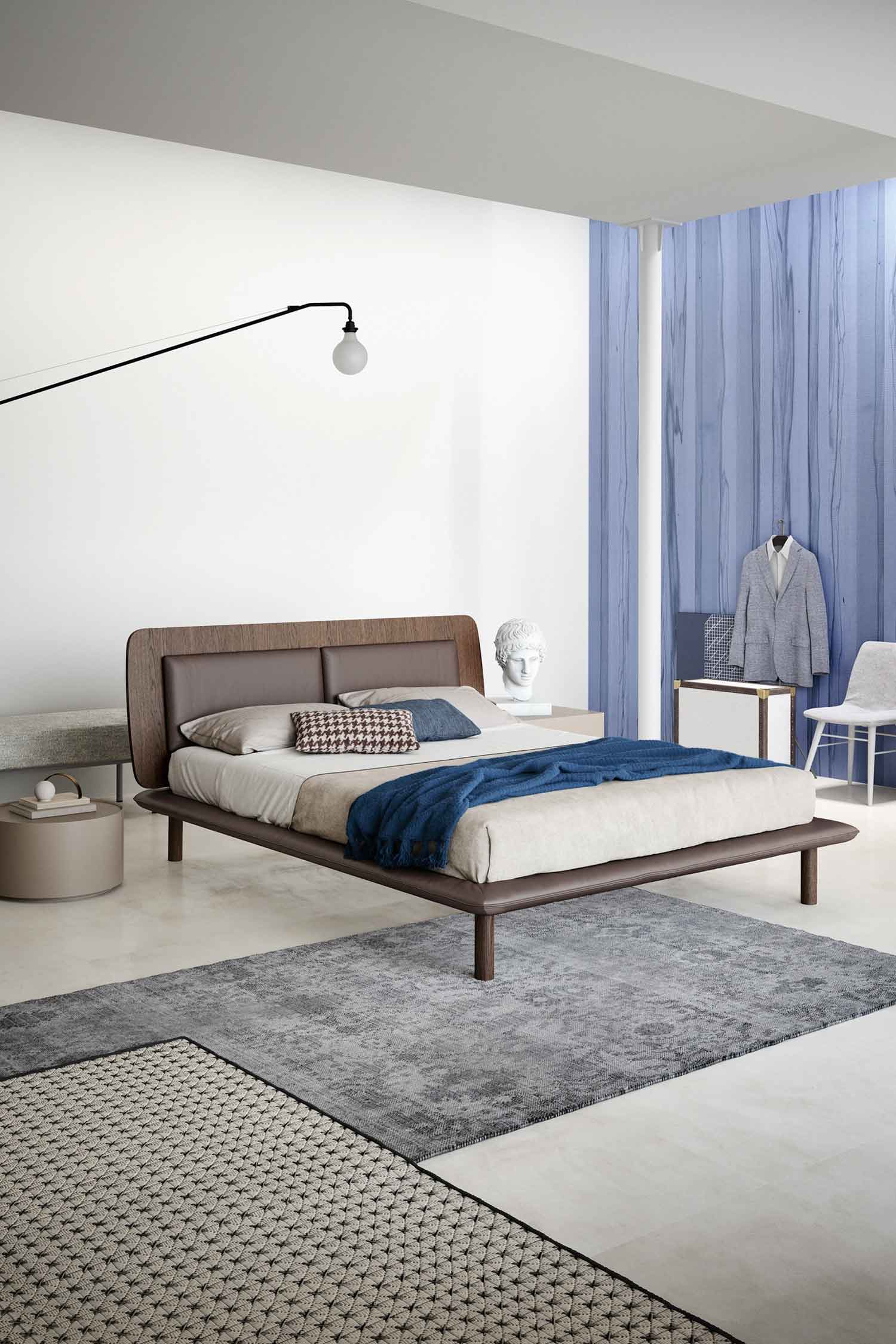 Contemporary bedroom featuring a dark wood bed frame with a leather headboard, a blue throw, a grey patterned rug, and a feature wall with vertically patterned blue wood panels.