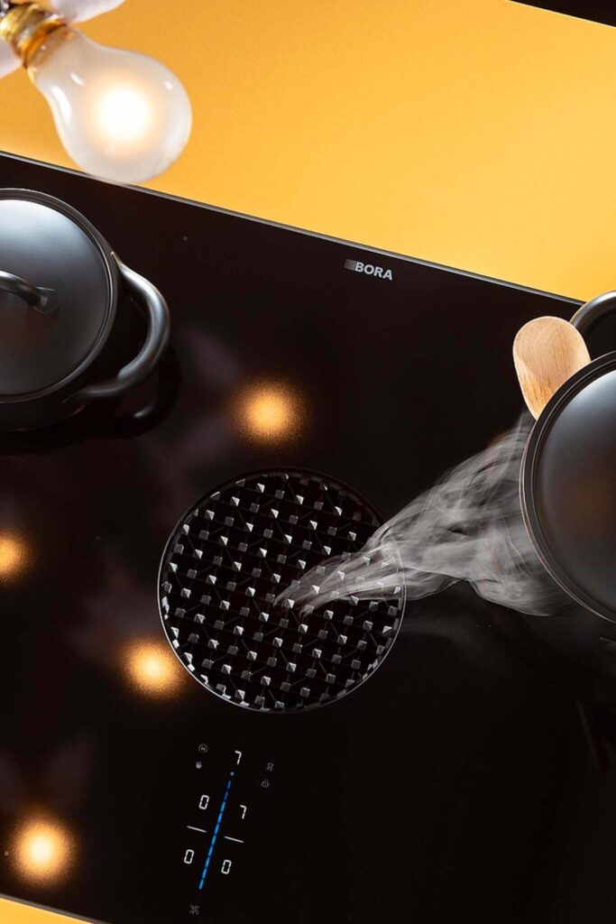 Steam from boiling pot being drawn into BORA X Pure central extractor on elegant black glass induction surface.